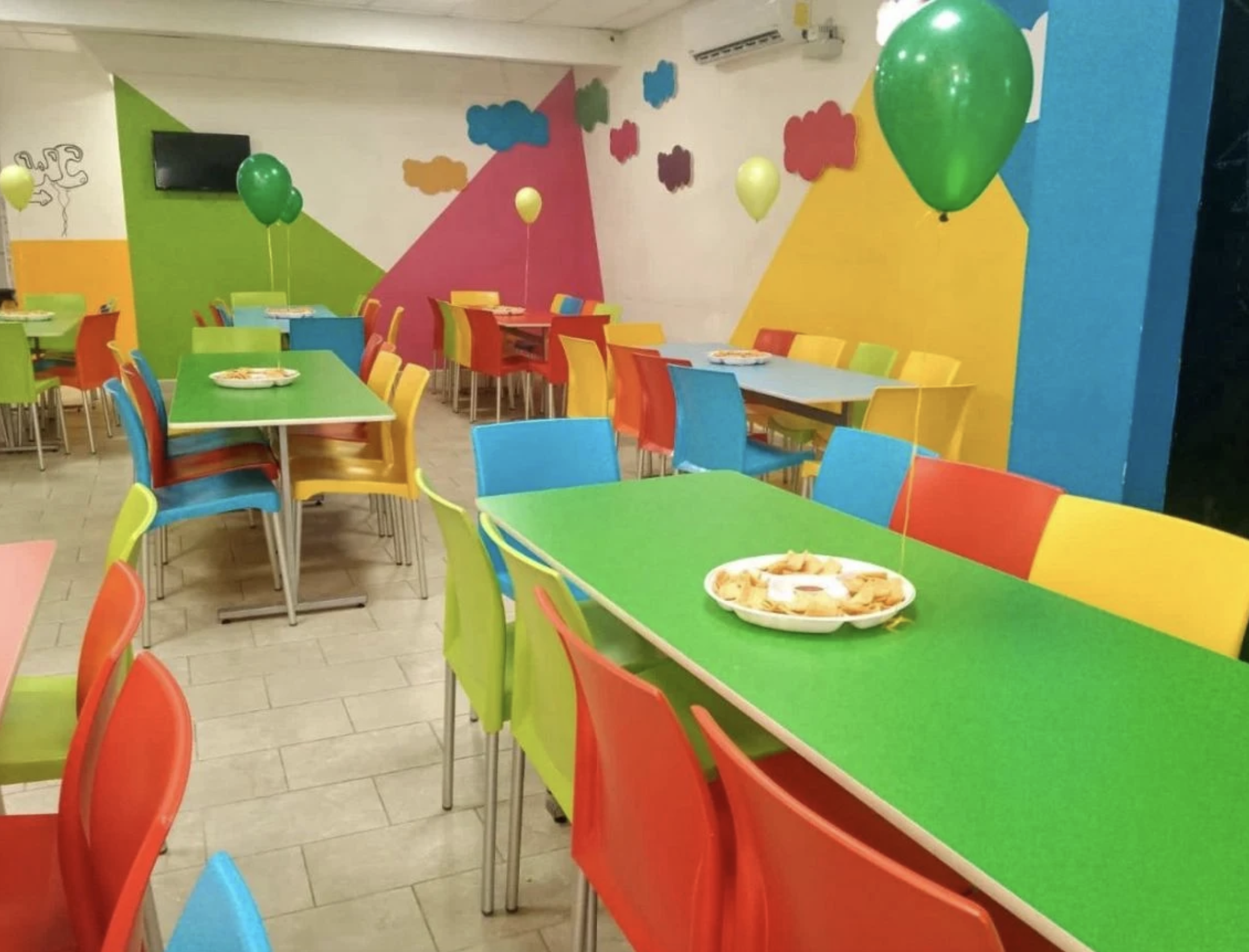 Salón de fiestas con mesas coloridas y globos